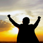 man looking at the sunset with fists in the air
