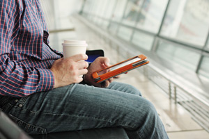 Man drinking coffee reading a tablet